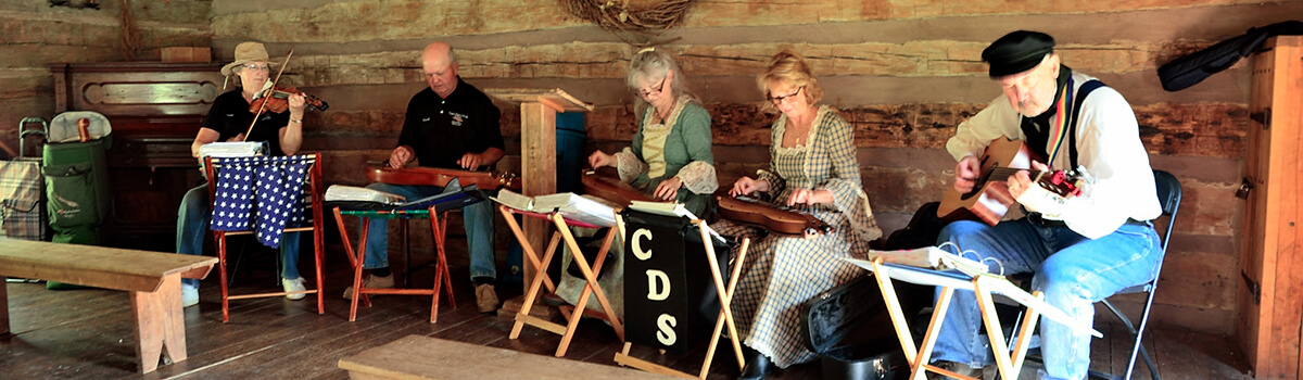 Corydon Dulcimer Society members gathered together outside on a sunny day playing their instruments